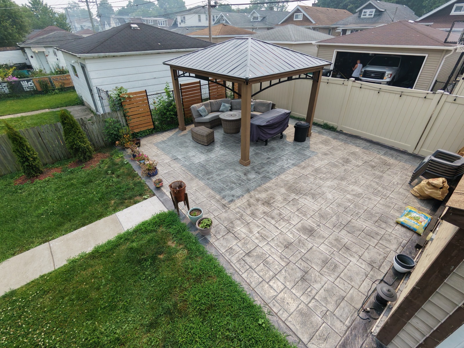 Aerial close-up of a stamped concrete patio with gazebo, sofa, and fire pit