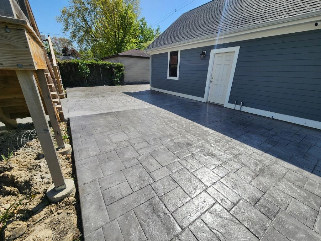 Finished ashlar-pattern stamped concrete patio beside a garage
