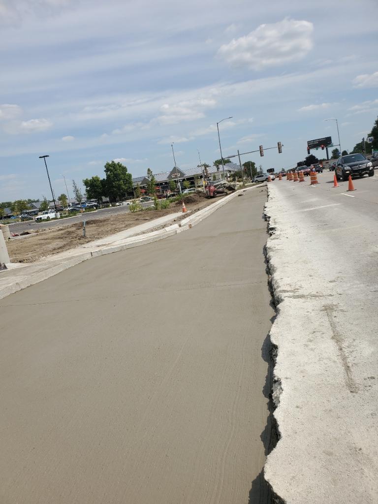Fresh concrete pour along a commercial roadway with traffic
