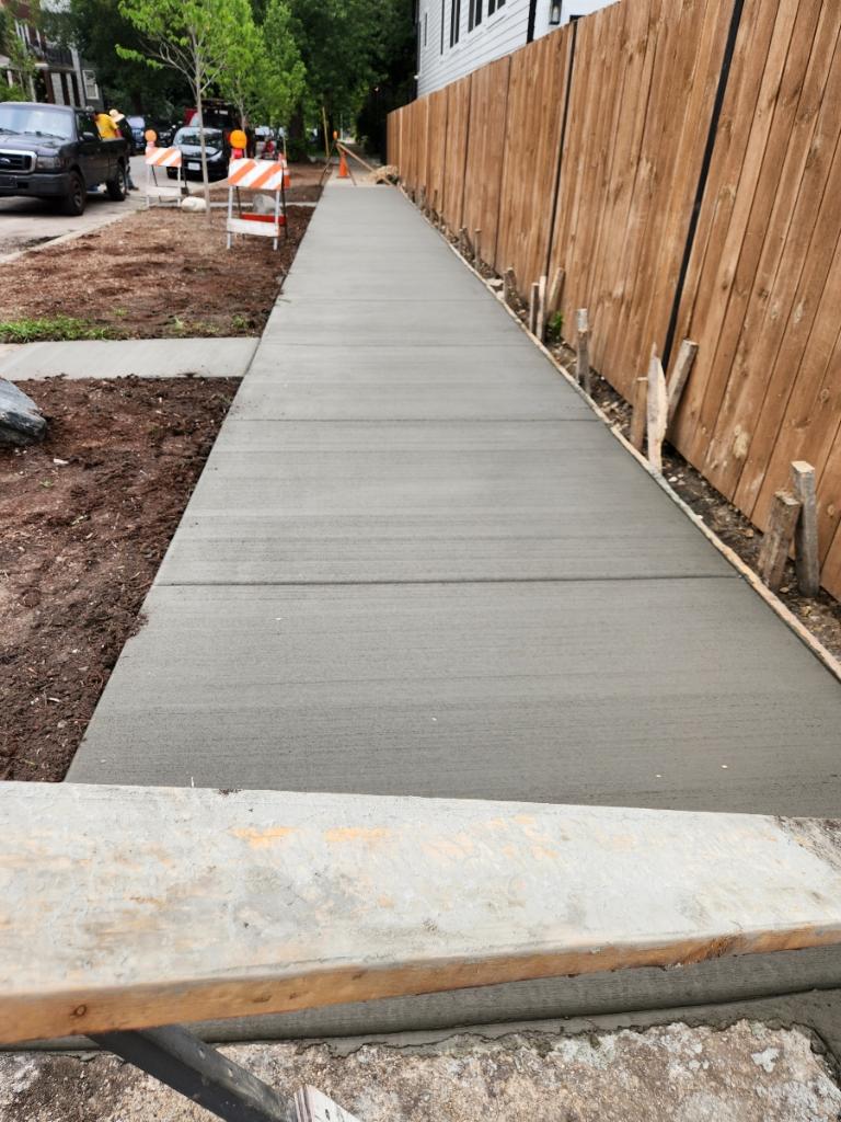 Freshly poured broom-finished sidewalk curing